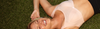 Hero banner Woman lying on grass wearing a sports bra with 'SPORTS BRAS' text above.