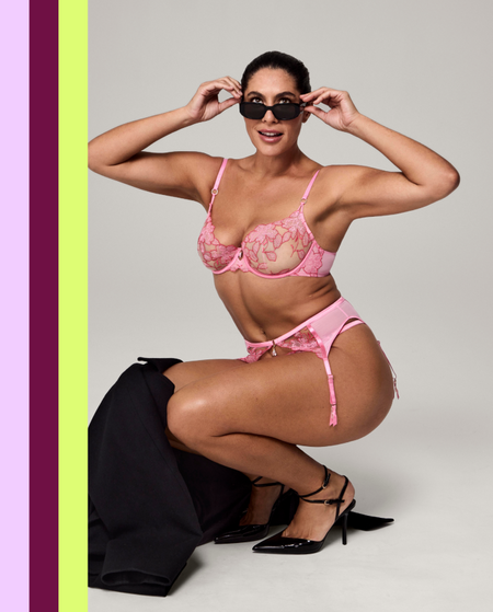 Woman wearing a pink lingerie set with sunglasses on a gray background