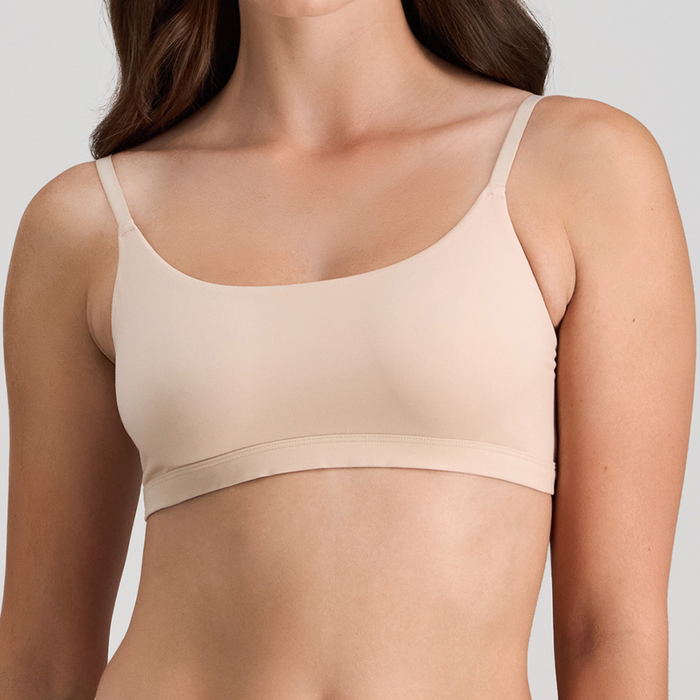 Beige bra worn by a person on a plain background