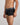Model wears Cotton Low-Rise Mens Trunk in BLACK. On body side view