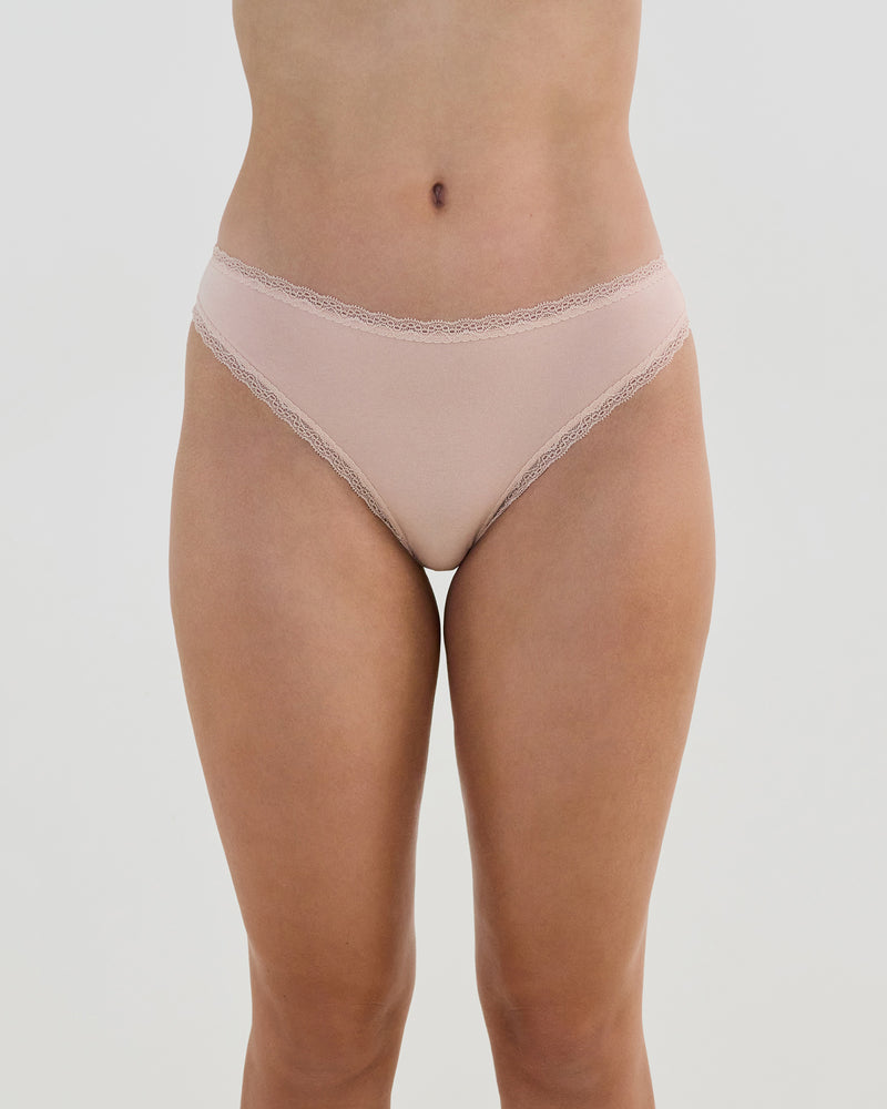 Model wears Stretch Cotton Thong in LATTE. On body front view