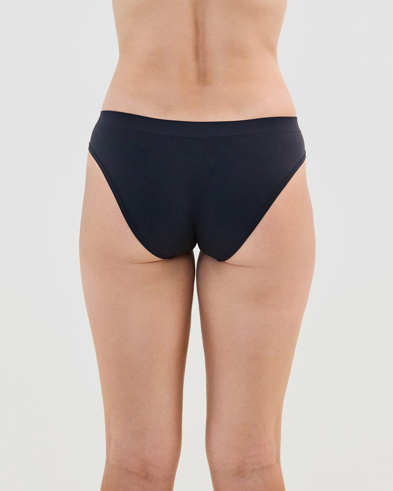 Model wears Seamless Soft Bikini in BLACK. On body back view