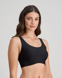 Model wears Comfit Collection Crop Top in BLACK. On body side view