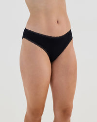 Model wears Stretch Cotton Bikini in BLACK. On body side view