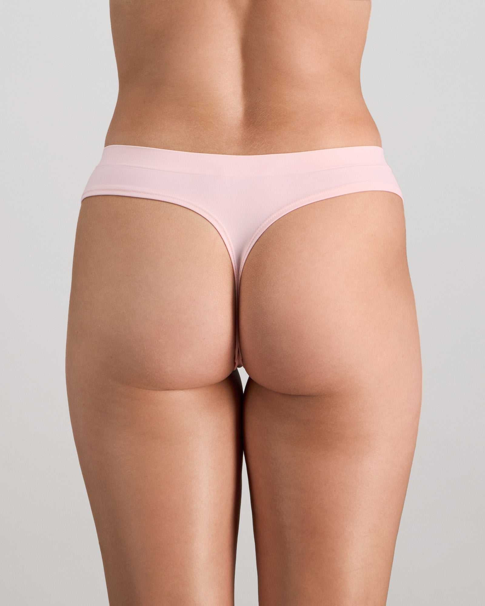 Model wears Seamless Soft Thong in ICY PINK. On body back view