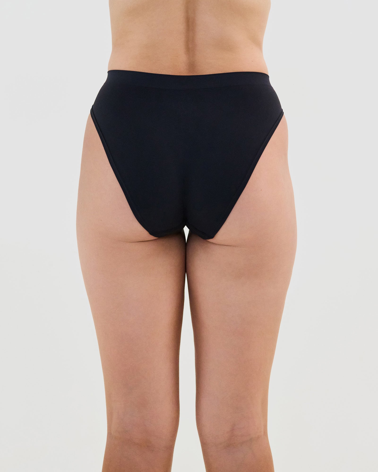 Model wears Seamless Soft High Cut Brief in BLACK. On body back view