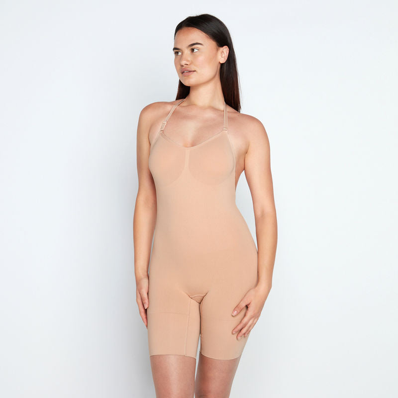 Model wears Medium Control Jumpsuit in CARAMEL. On body side view