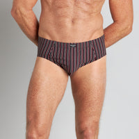Model wears Cotton Stretch Mens Brief in BLACK/RHUBARB STRIPE. On body front view