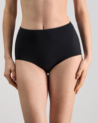 Model wears Freestyle Full Brief in BLACK. On body front view