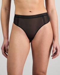 Model wears Sheer Essence Thong in BLACK. On body front view