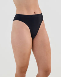 Model wears Seamless Soft High Cut Brief in BLACK. On body side view