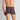 Model wears Cotton Stretch Mens Trunk in BLACK/RHUBARB STRIPE. On body back view