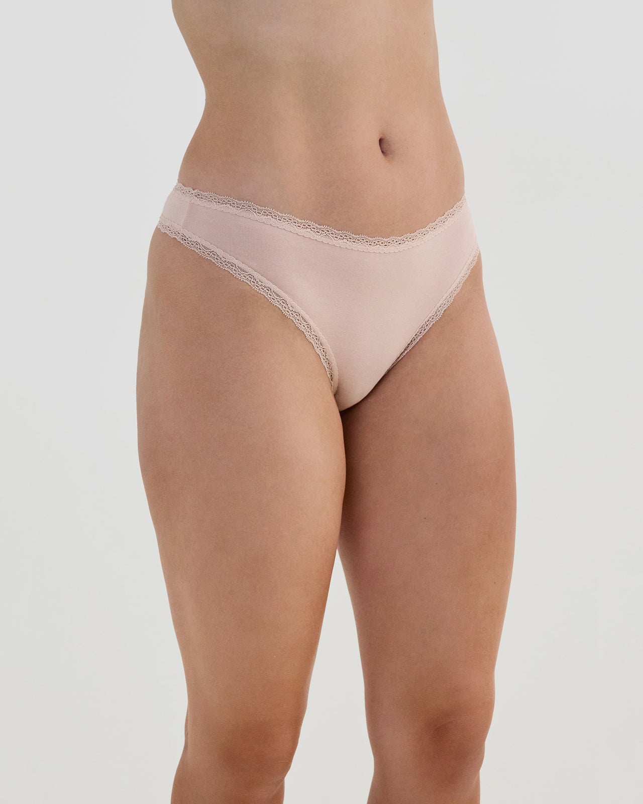 Model wears Stretch Cotton Thong in LATTE. On body side view