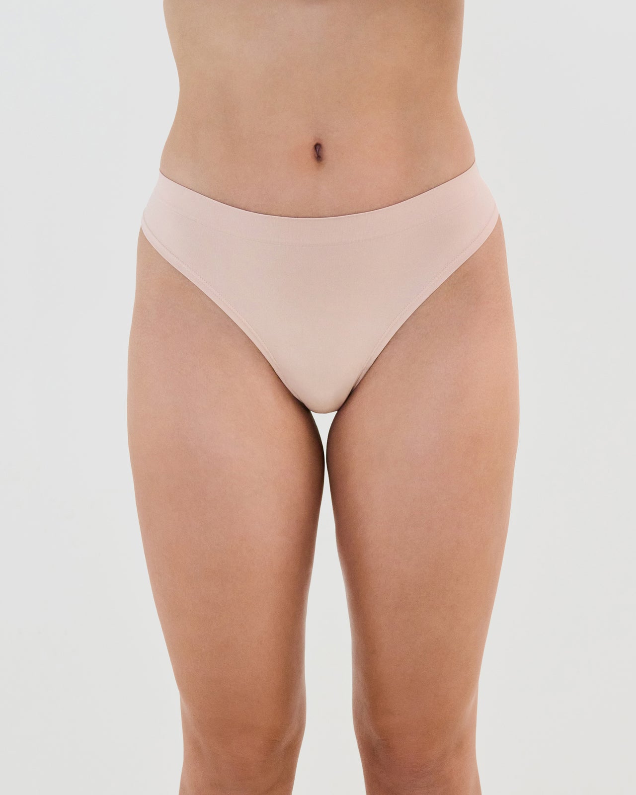 Model wears Seamless Soft Thong in LATTE. On body front view