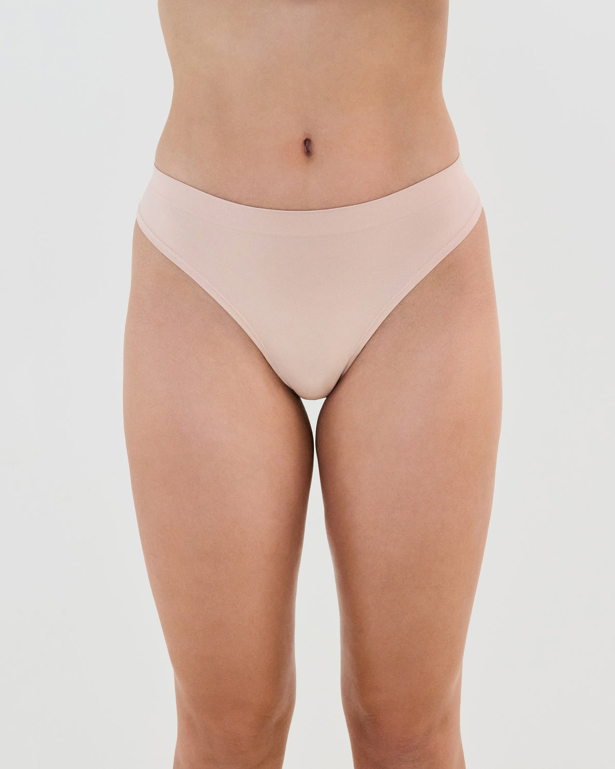 Model wears Seamless Soft Thong in LATTE. On body front view