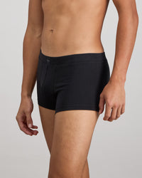 Model wears High Tech Cotton Mens Trunk in BLACK. On body side view