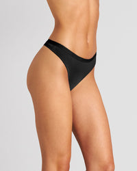 Model wears Body Cotton Thong in BLACK. On body side view
