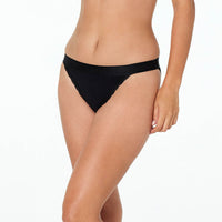 Model wears Cotton Logo Tanga in BLACK. On body side view