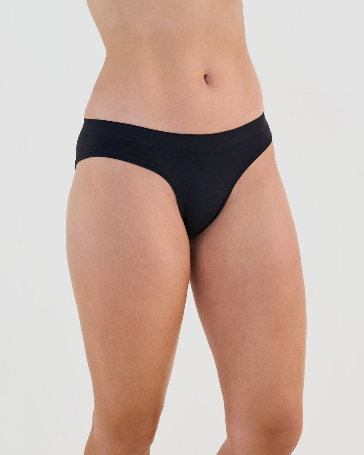 Model wears Seamless Soft Bikini in BLACK. On body side view