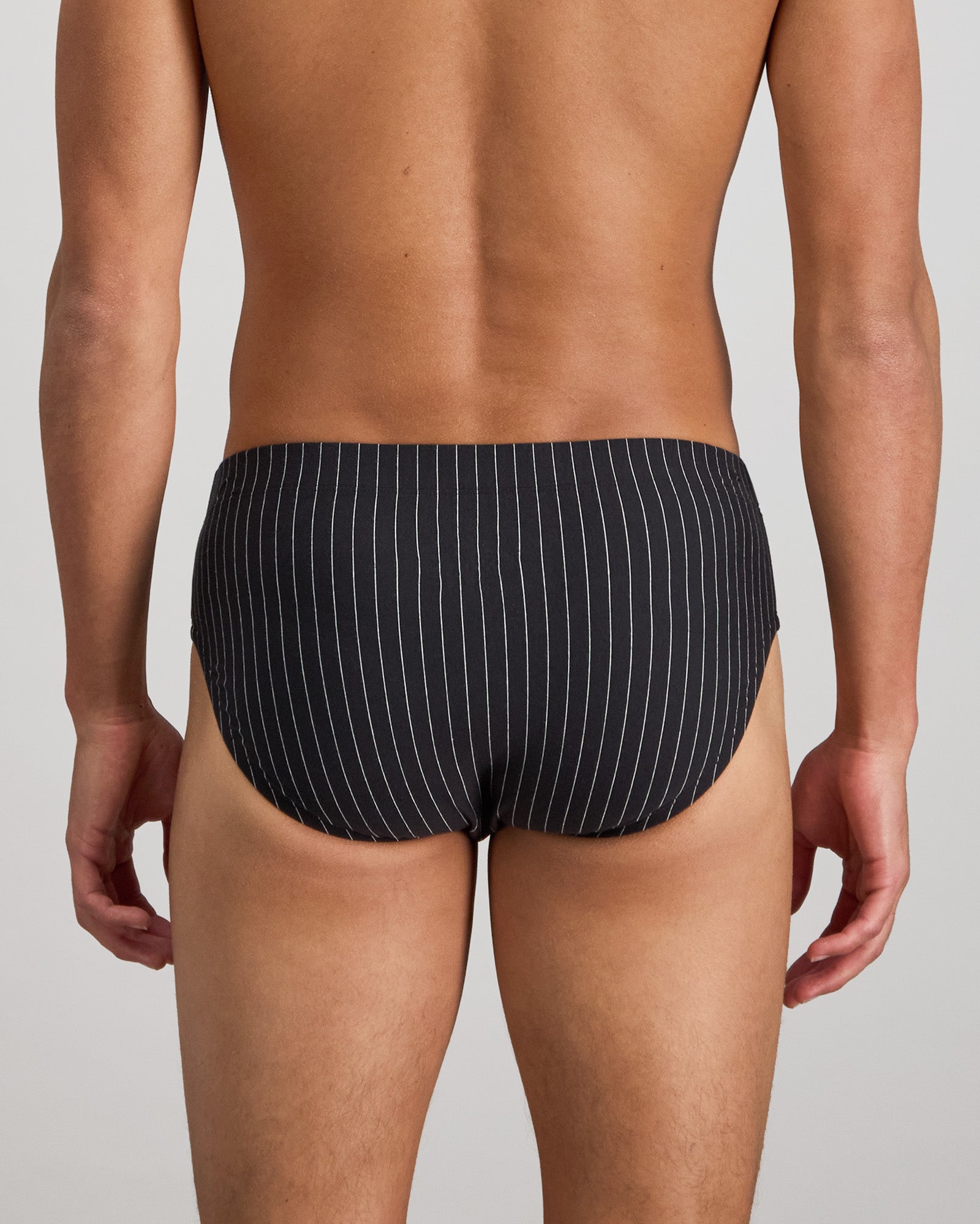 Model wears Cotton Stretch Mens Brief in BLACK PINSTRIPE. On body back view