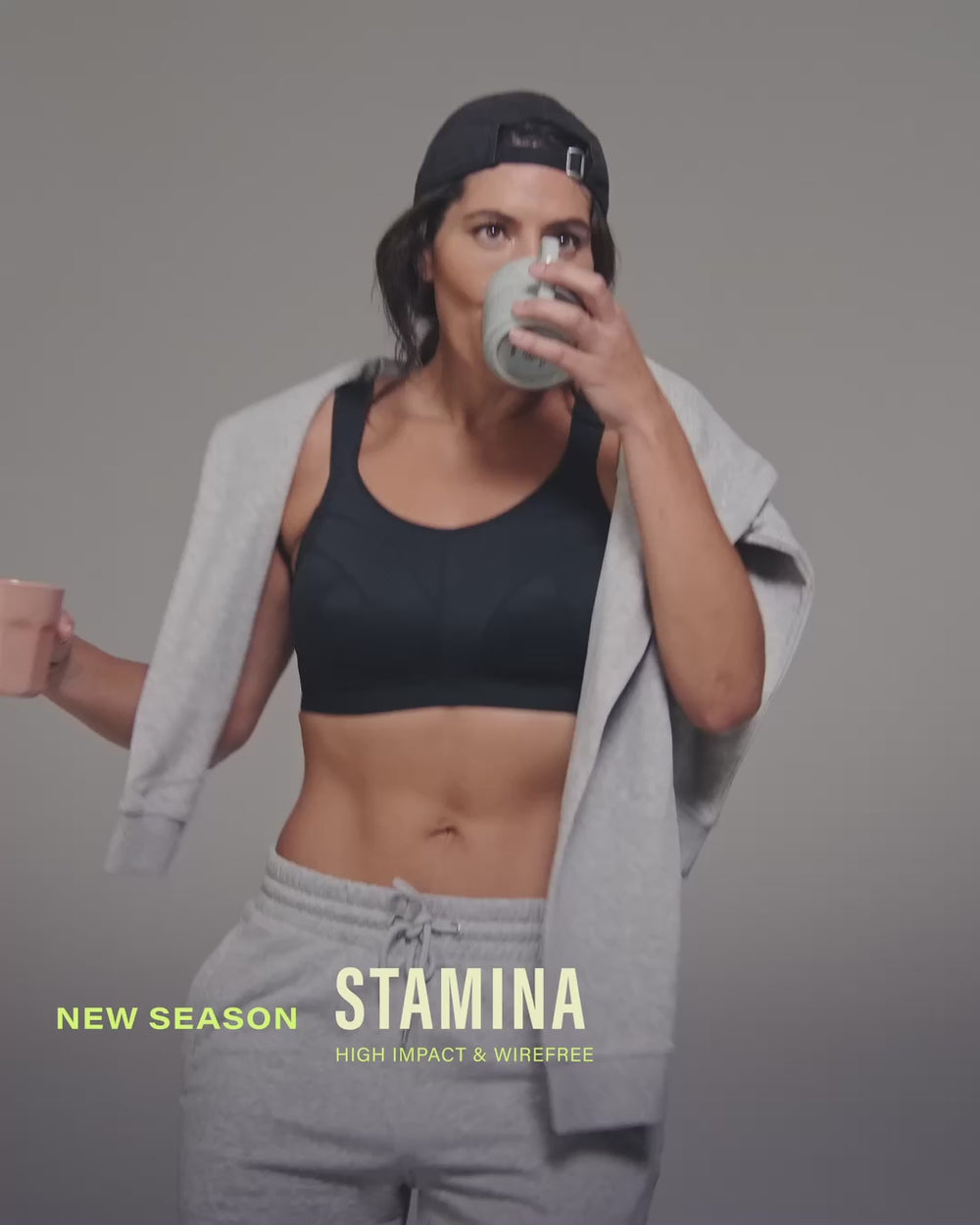 model-holds-two-coffee-cups-wearing-black-sports-bra