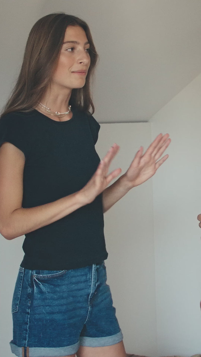 model being measured for a bra, posing in a black bra crop top