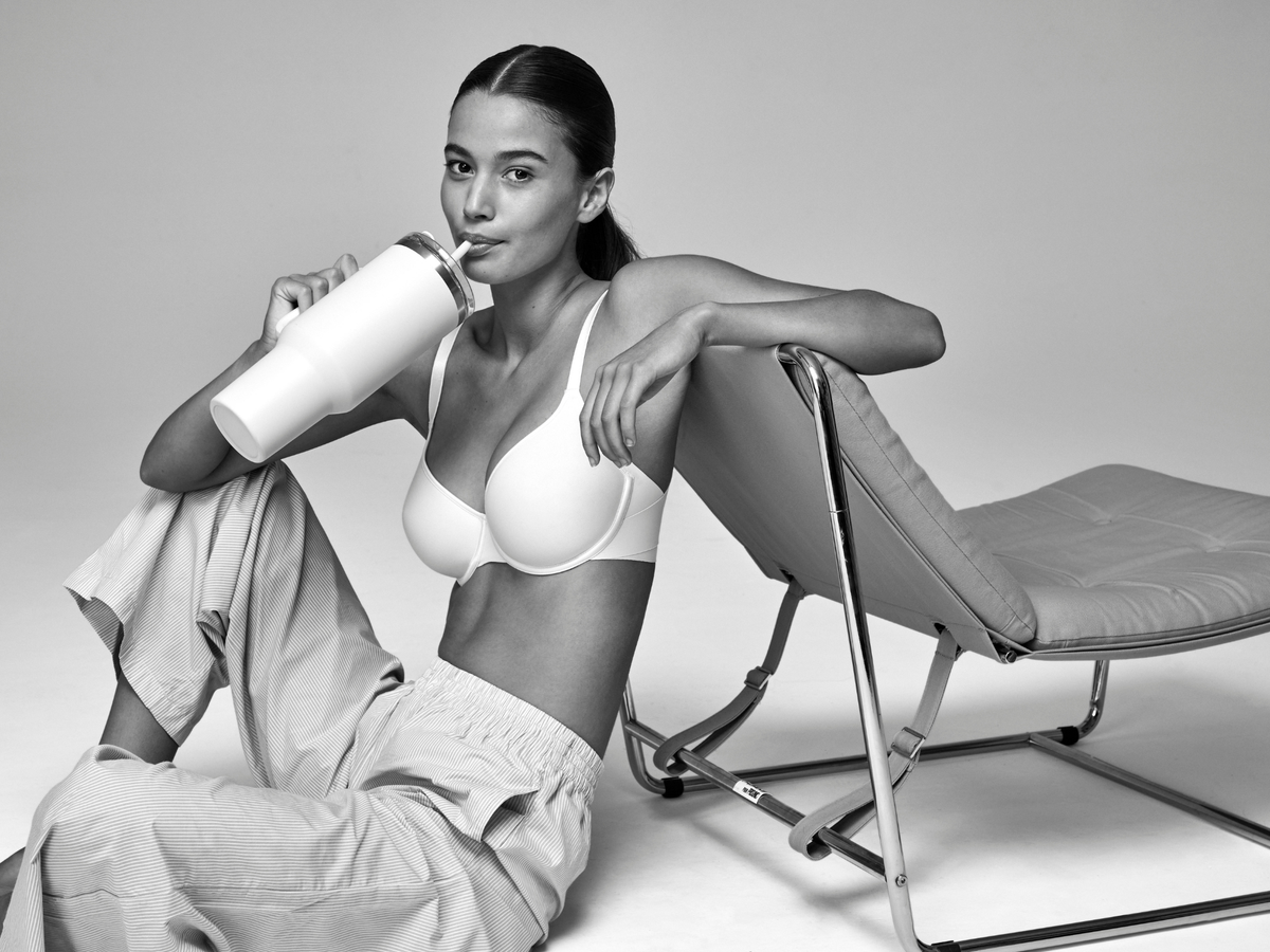 Woman in a white bra sitting on a modern chair with a white background
